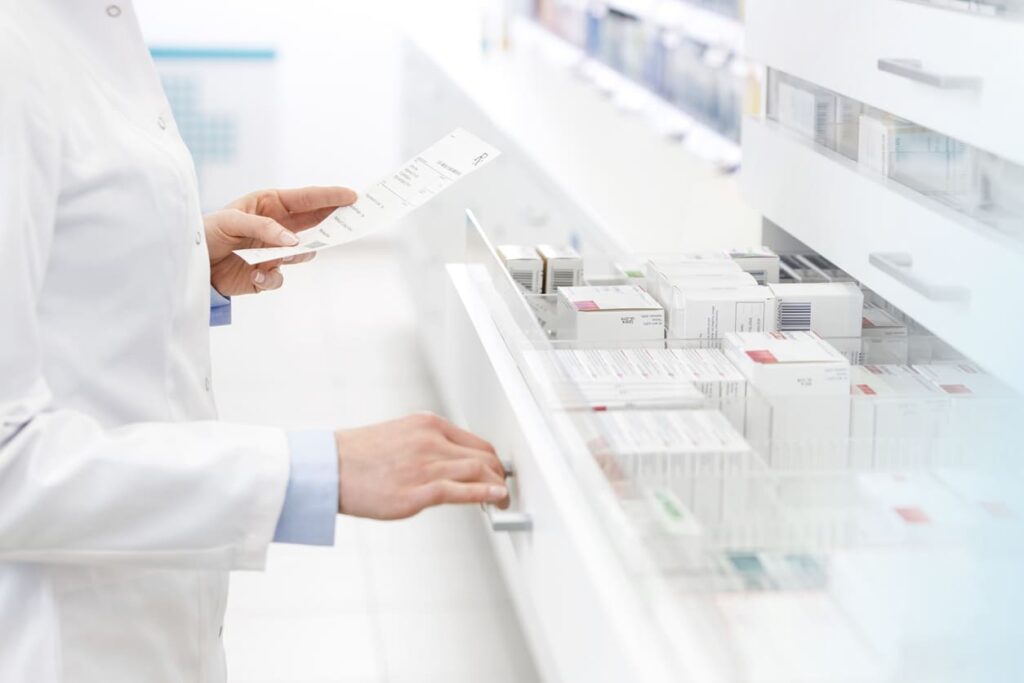 Apotheker öffnet Schublade mit Medikamenten.