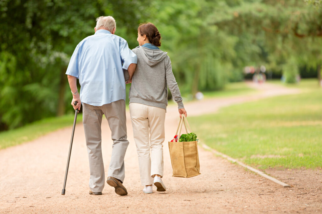 Pflegende Angehörige und Patient spazieren